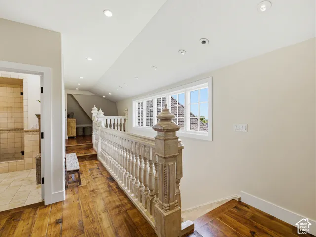 Hardwood flooring throughout the upper level hallway, featuring a carved balustrade, recessed lighting, and multipane windows