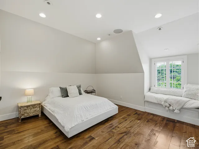 Spacious room featuring wood-finish flooring, a built-in window seat, recessed lighting, and a window with white shutters