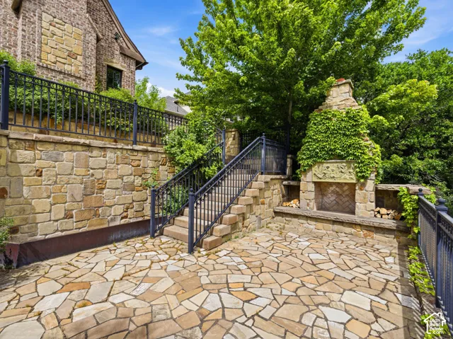 Expansive flagstone patio featuring a built-in stone fireplace with decorative carving and integrated wood storage