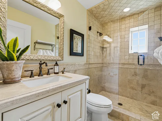 Bathroom featuring a glass-enclosed shower with tile surround, a built-in window, a vanity with a rectangular sink, and an ornate framed mirror