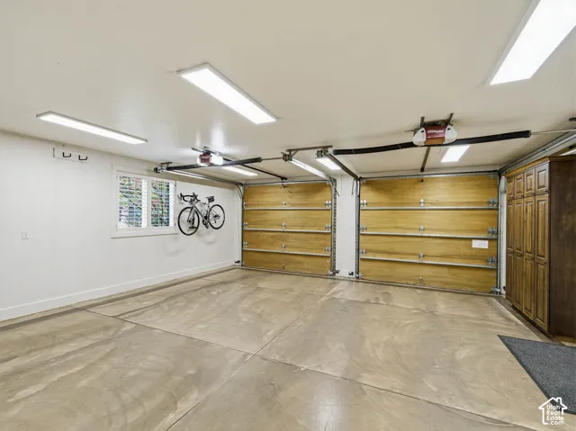 Two-car garage featuring a concrete floor, two wood-paneled garage doors, and built-in wood cabinetry