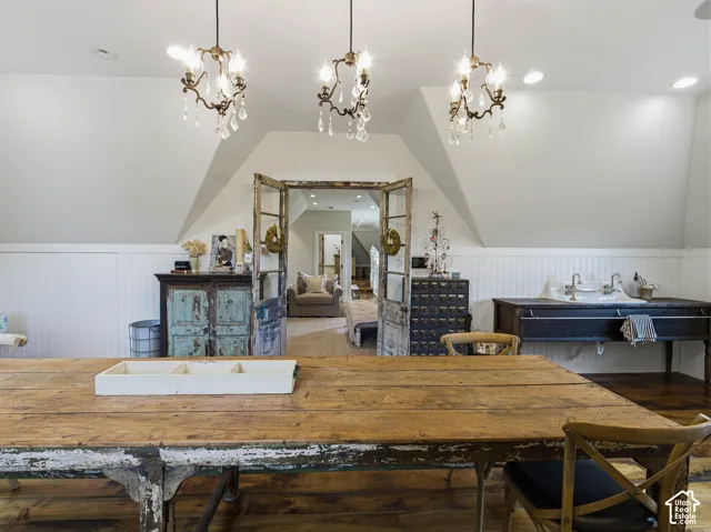 Attic living area featuring three crystal-accented chandeliers, wood-finish flooring, and white paneled wainscoting