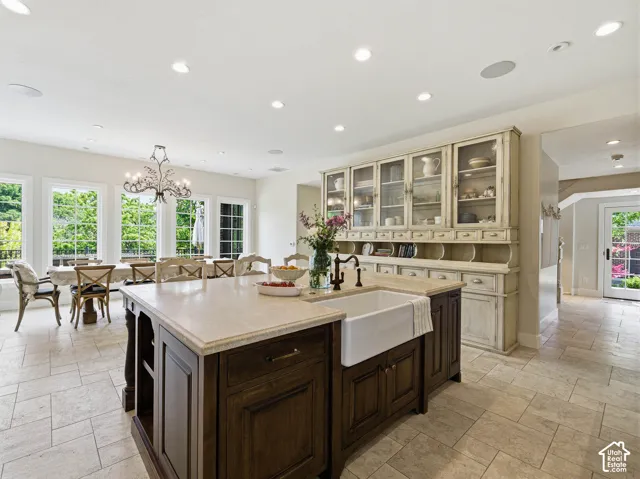 Spacious kitchen island featuring a farmhouse sink, dark wood-finish cabinetry, and a light-toned countertop