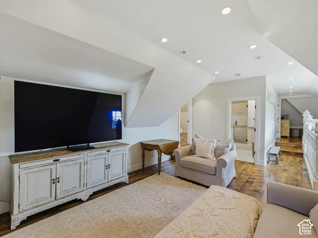 Finished upper-level space featuring recessed lighting, wood-finish flooring, and a white distressed-look media console