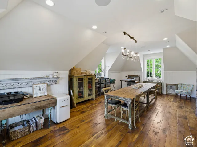 Vaulted ceiling room featuring hardwood flooring and multiple windows