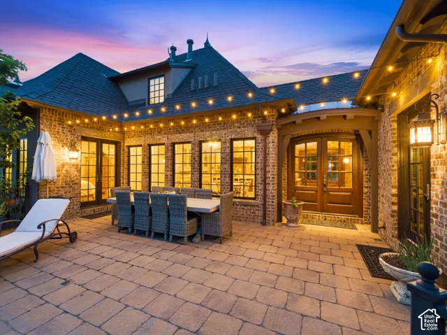 Extensive paver patio featuring brick exterior architecture and multiple French-style doors