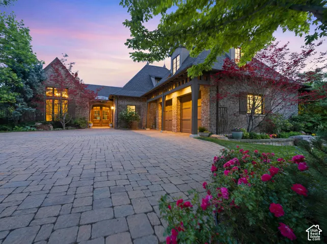 Stone and brick exterior residence featuring a paver driveway, multiple dormer windows, and a three-car garage