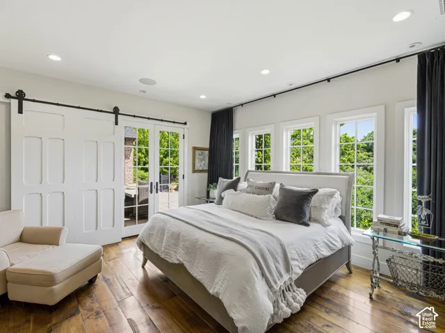 Hardwood flooring throughout, featuring a wall of multiple windows, recessed lighting, and a barn door entry to an outdoor space