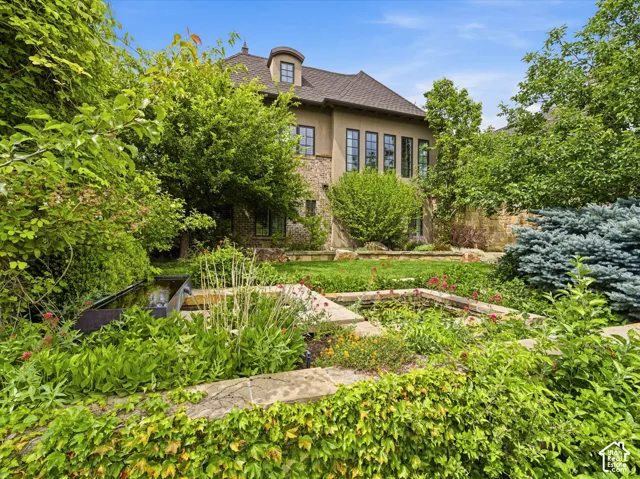 Multi-level terraced garden featuring extensive plantings, a water feature, and stone retaining walls