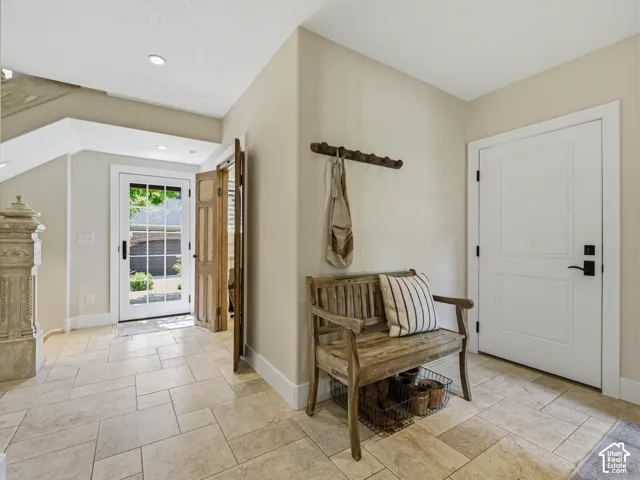 Entryway featuring light-toned tile flooring, recessed lighting, a paneled white door with black hardware, a glass-paned exterior door, and a carved newel post