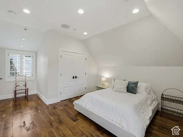 Attic room featuring wood-finish flooring, recessed lighting, white double doors with matte black hardware, and a window with plantation shutters
