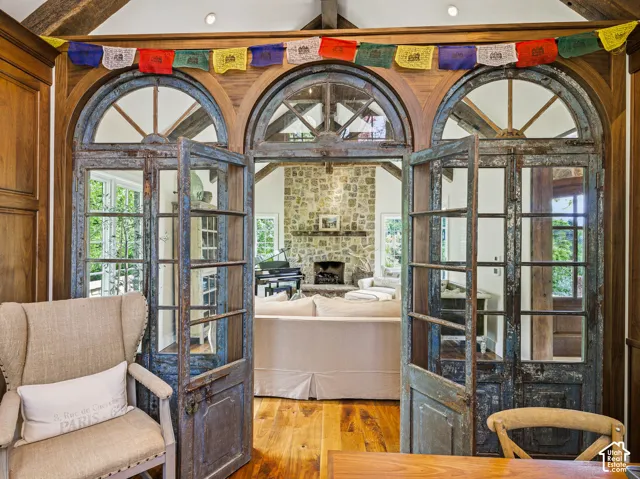 Distressed wood-frame French doors with arched transoms open to a living space featuring a stone fireplace