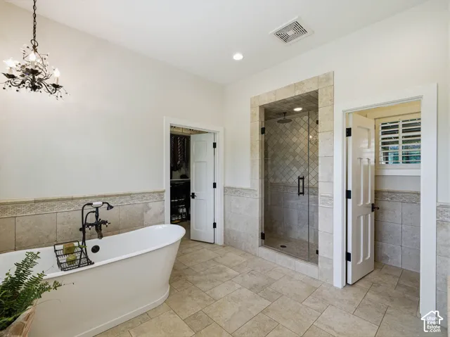 Spacious bathroom featuring a freestanding soaking tub with a floor-mounted fixture, a glass-enclosed shower with tile surround, and neutral-toned tile flooring
