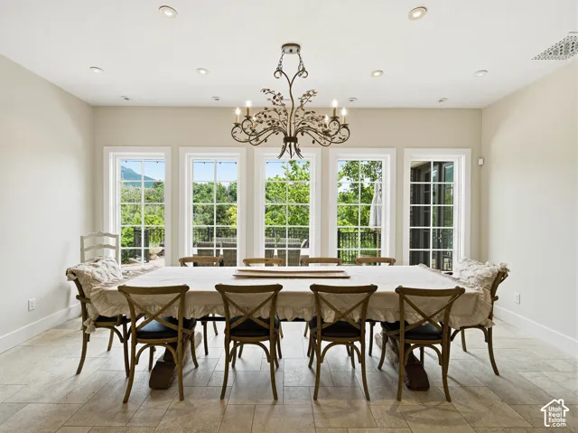 Spacious dining area featuring a prominent chandelier, recessed lighting, and large windows