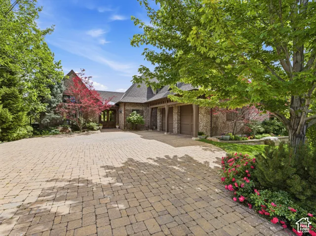 Brick exterior residence featuring a multi-car garage, pitched roofline, and a substantial paver driveway