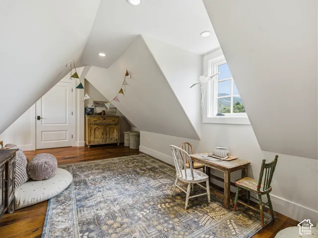 Attic space featuring sloped ceilings, recessed lighting, and wood-finish flooring