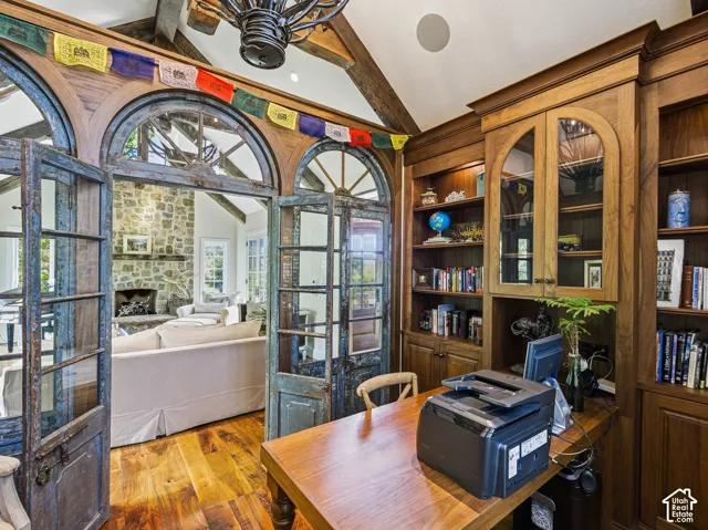 Wood-finish flooring with built-in wood cabinetry, integrated desk, and arched glass-paneled doors