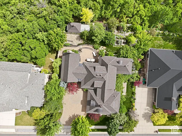 Sprawling residential property featuring extensive mature landscaping, multiple paved patios, and a gravel driveway
