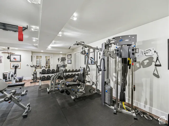Dedicated fitness space featuring rubberized flooring, recessed lighting, white walls, and French doors with glass panels
