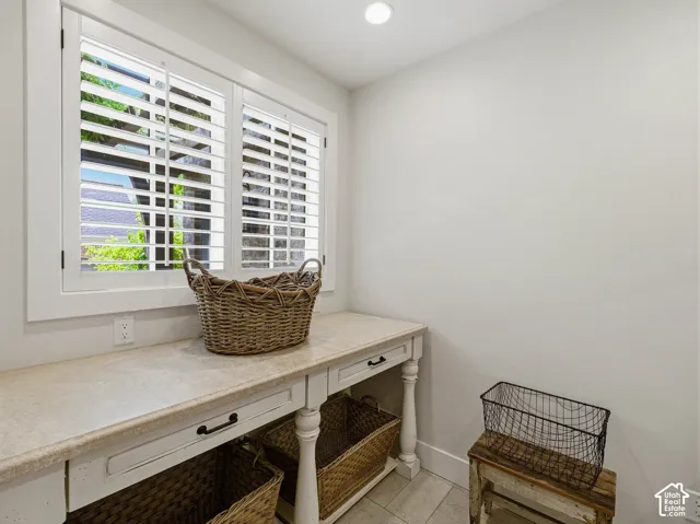 Bright interior space featuring a window with white plantation shutters, a recessed ceiling light, and light-toned tile flooring