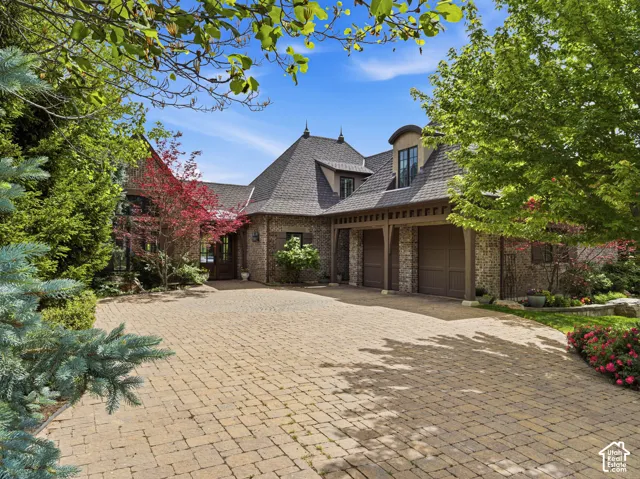 Stone paver driveway leading to a brick and stone exterior residence with a multi-gabled roofline