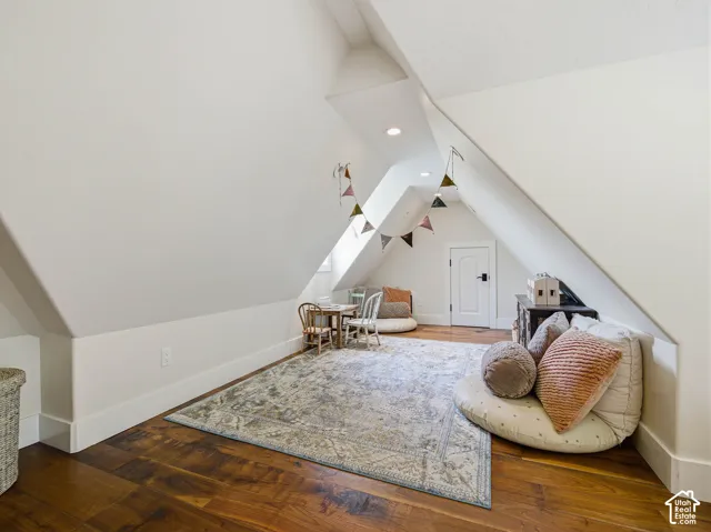 Attic space featuring wood-finish flooring, white sloped ceilings, and recessed lighting