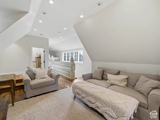 Upper-level landing featuring vaulted ceilings, recessed lighting, and rich wood-finish flooring