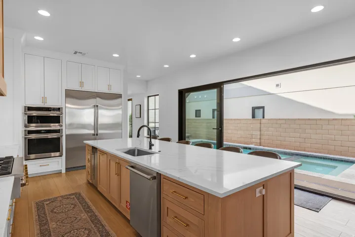 Spacious kitchen featuring a large island with a countertop, integrated sink, and seating, alongside wood-finish flooring
