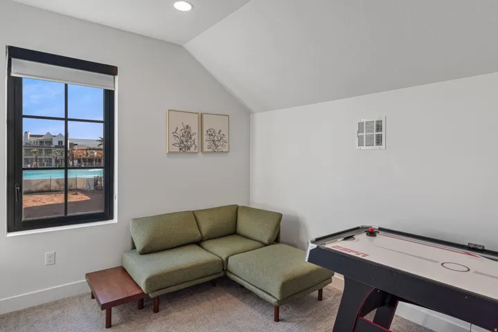 Interior room featuring a large black-framed window with grid panes, recessed lighting, and an angled ceiling line