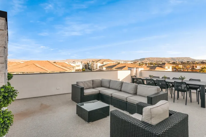 Expansive rooftop patio featuring a light-colored textured surface, a substantial perimeter wall, and a stone-clad architectural element
