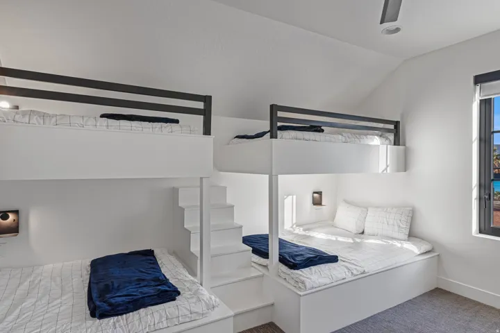 Integrated bunk beds featuring built-in stair access, individual lighting fixtures, and a vaulted ceiling