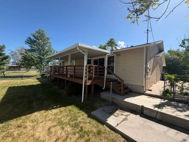 Expansive outdoor deck with a covered patio, featuring a wooden railing and steps