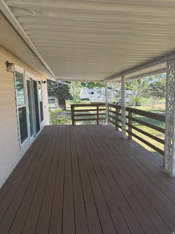 Expansive covered outdoor deck featuring wood-finish flooring, a white metal ceiling, and decorative railing elements