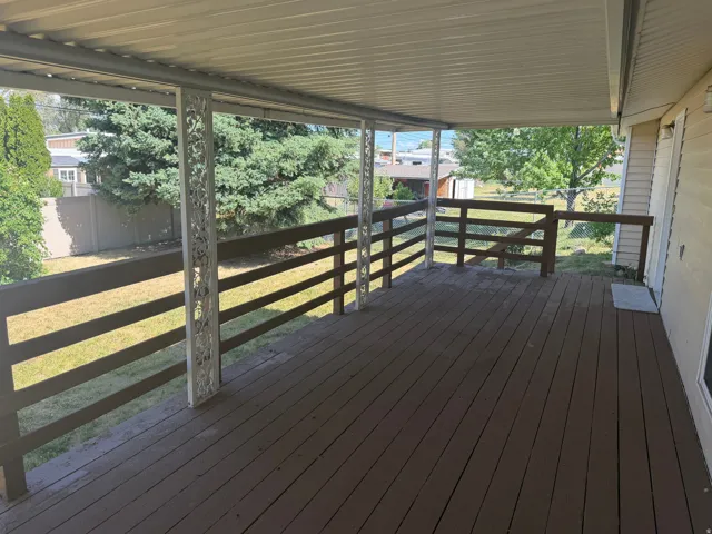 Expansive covered deck featuring wood-finish flooring and decorative metal support columns