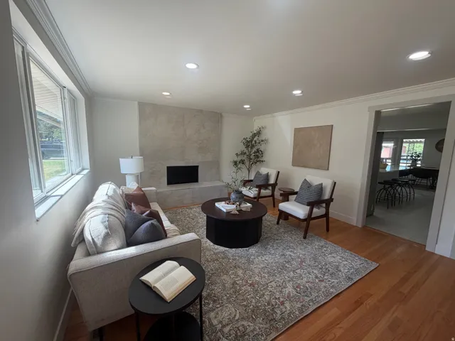 Living area featuring wood-finish flooring, recessed lighting, and a prominent fireplace with a stone-finish facade
