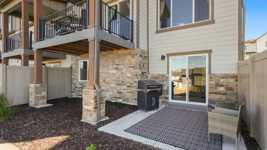 Private patio space featuring a concrete slab, sliding glass door access, and an exterior wall clad in horizontal siding and stone veneer