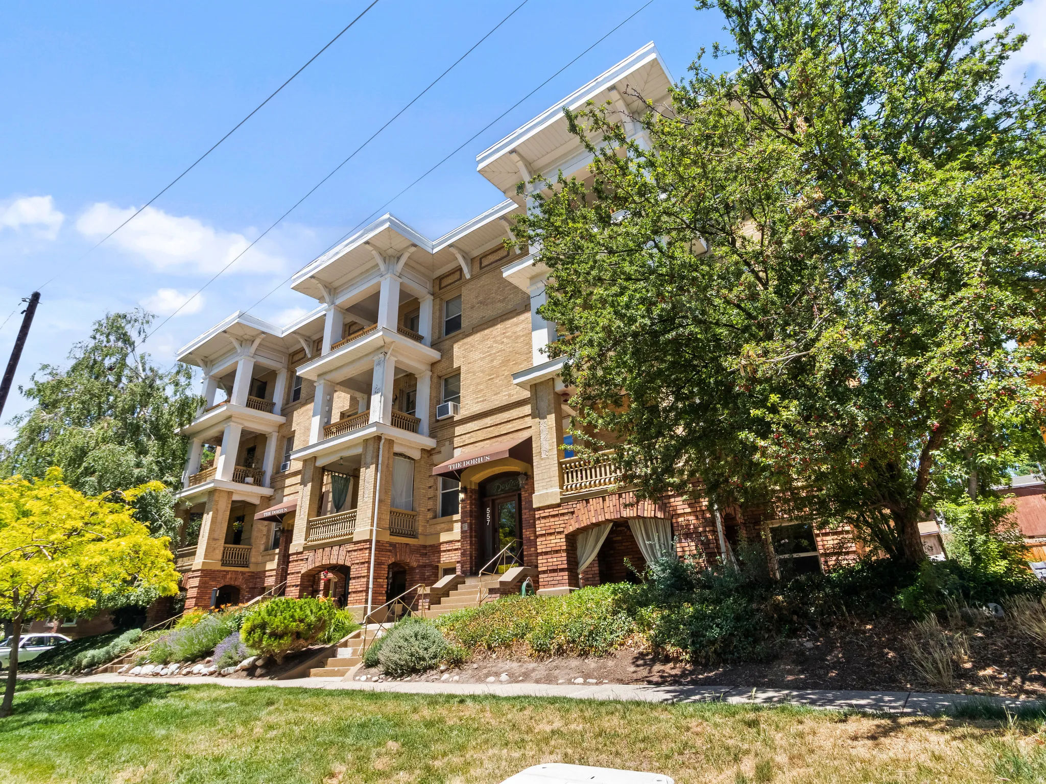 Brick building with multi-level balconies featuring intricate white columns and detailed trim