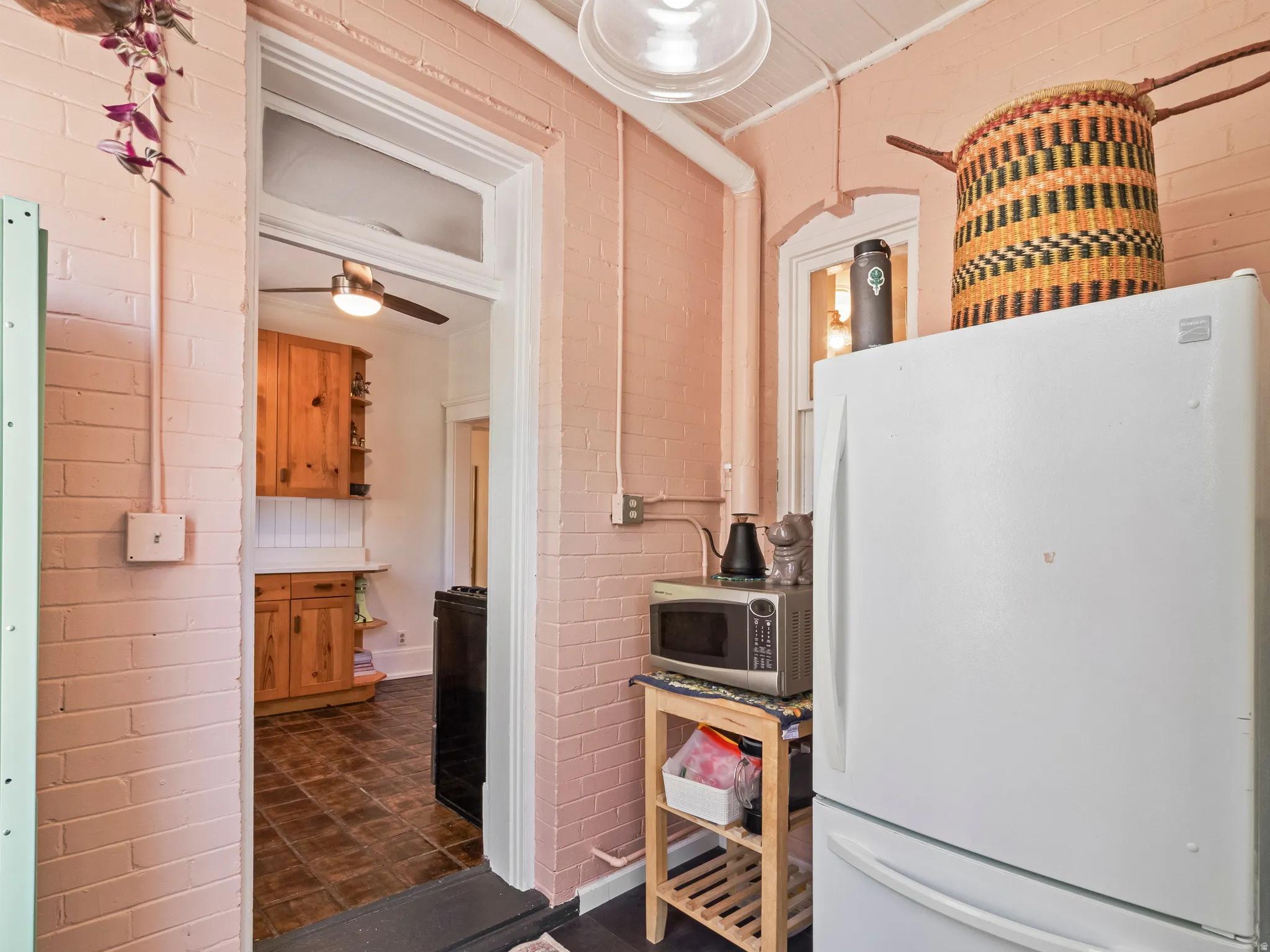 Kitchen space featuring brick walls, a built-in light fixture, and an arched window