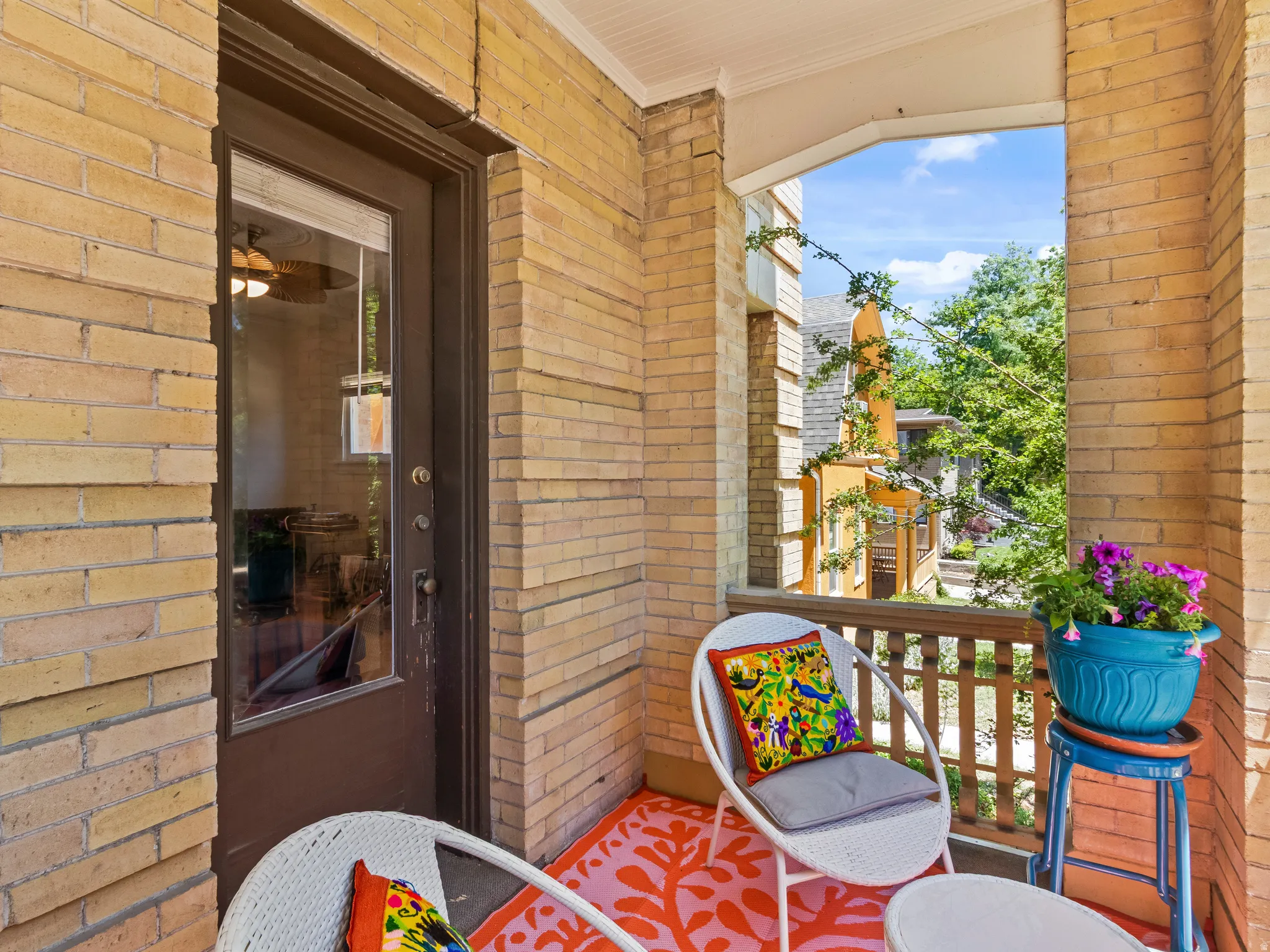 Brick exterior balcony with wooden railing, a glass-paned door, and natural light