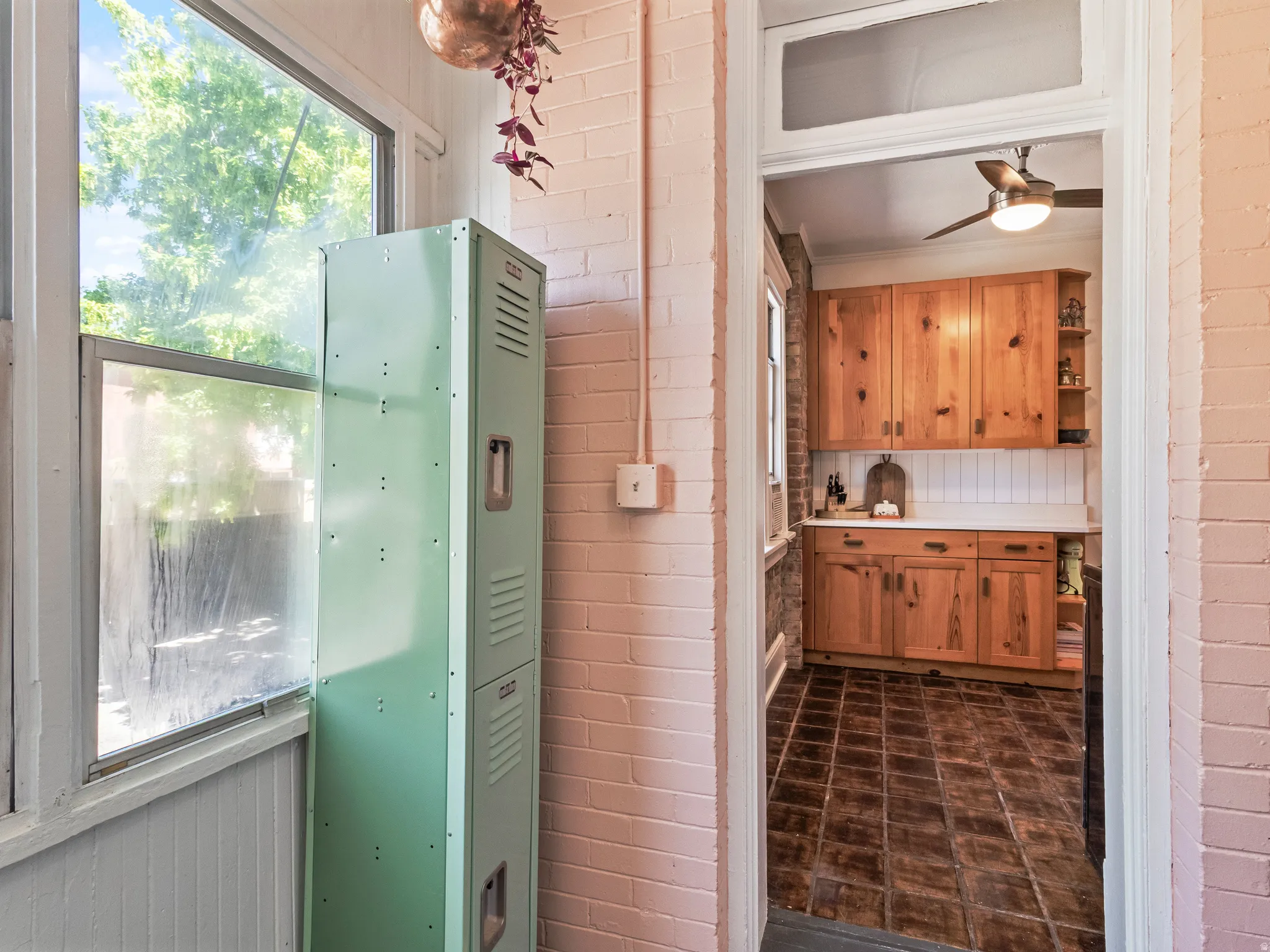 Archway opening to a kitchen featuring warm-toned wood cabinetry, white countertops, and a subway tile backsplash