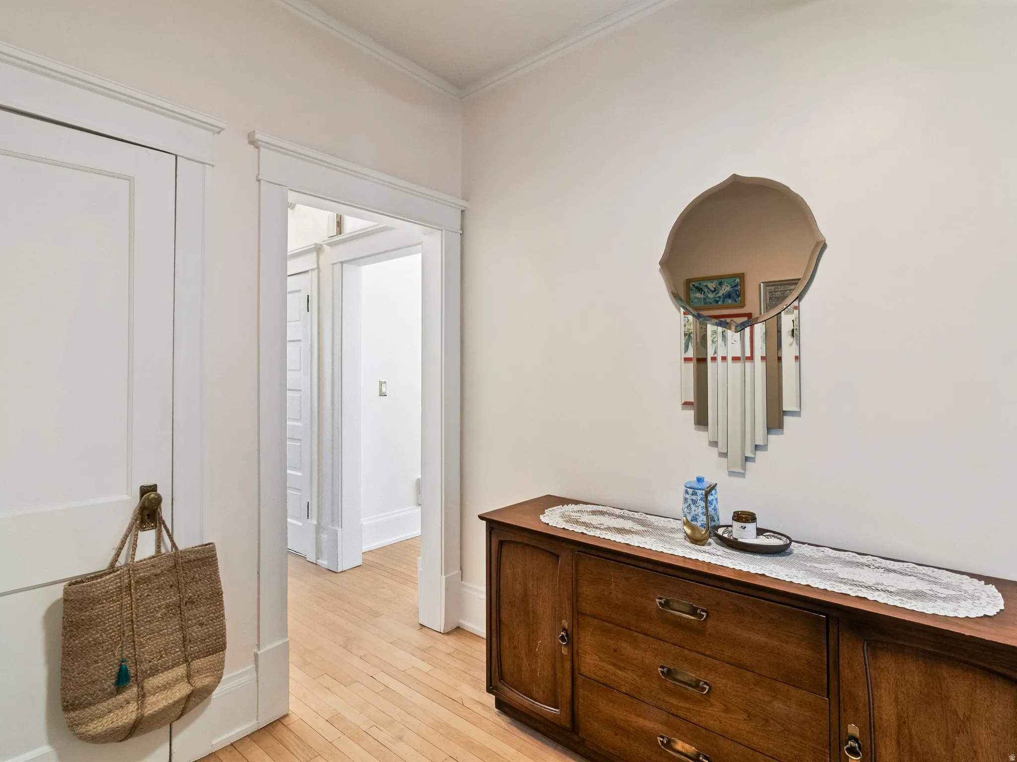 Hardwood flooring throughout featuring white trim and crown molding