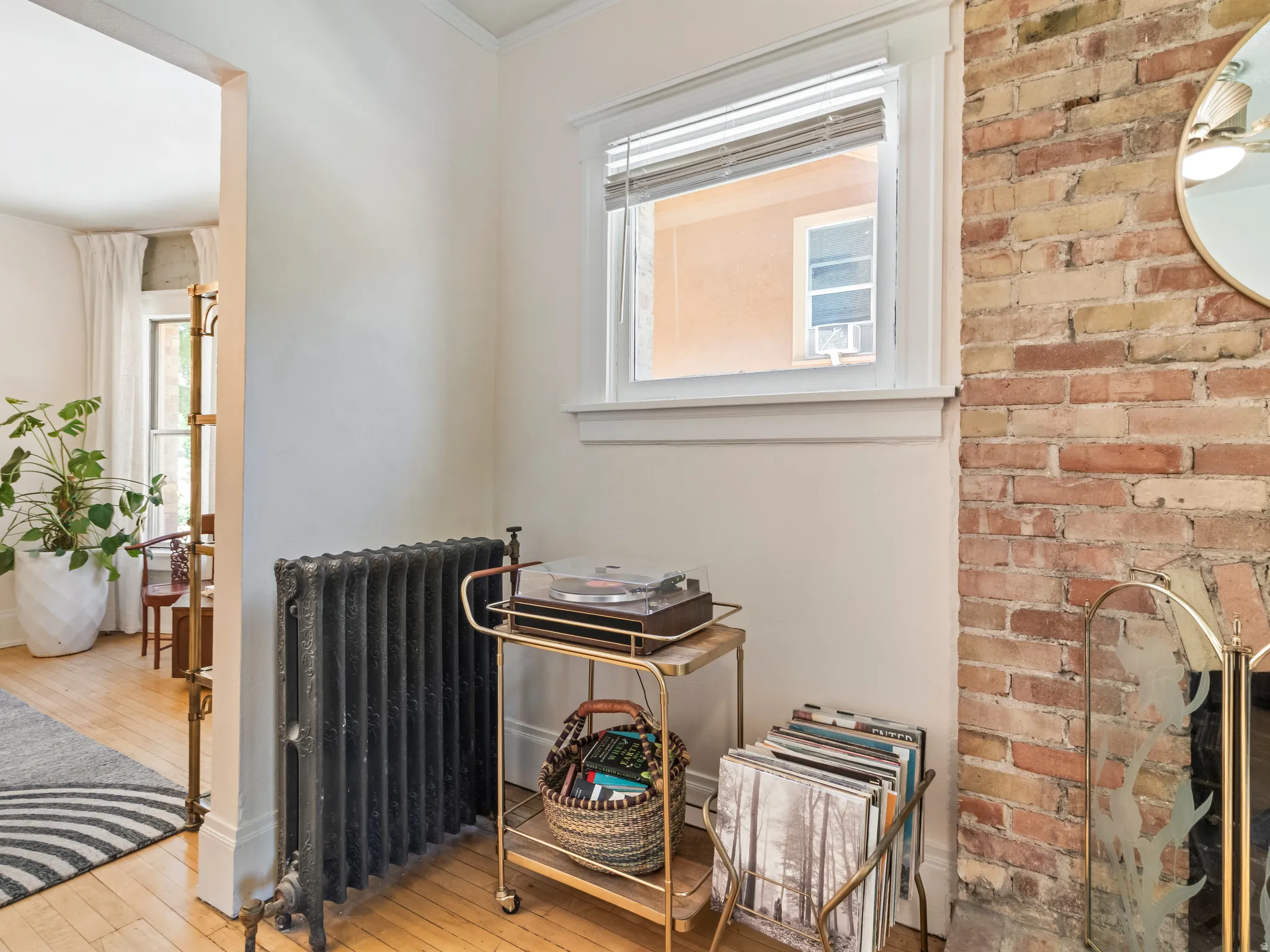 Exposed brick wall feature with a white window frame and a cast iron radiator