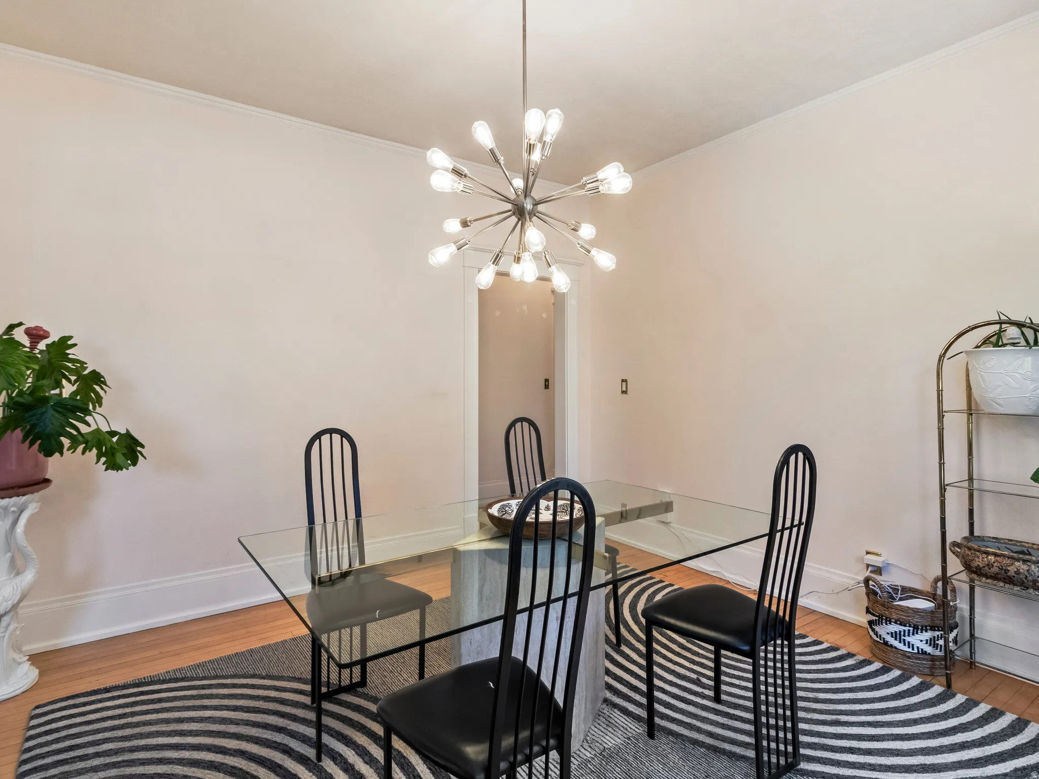 Dining area featuring a contemporary sputnik chandelier, light wood-finish flooring, and white baseboards