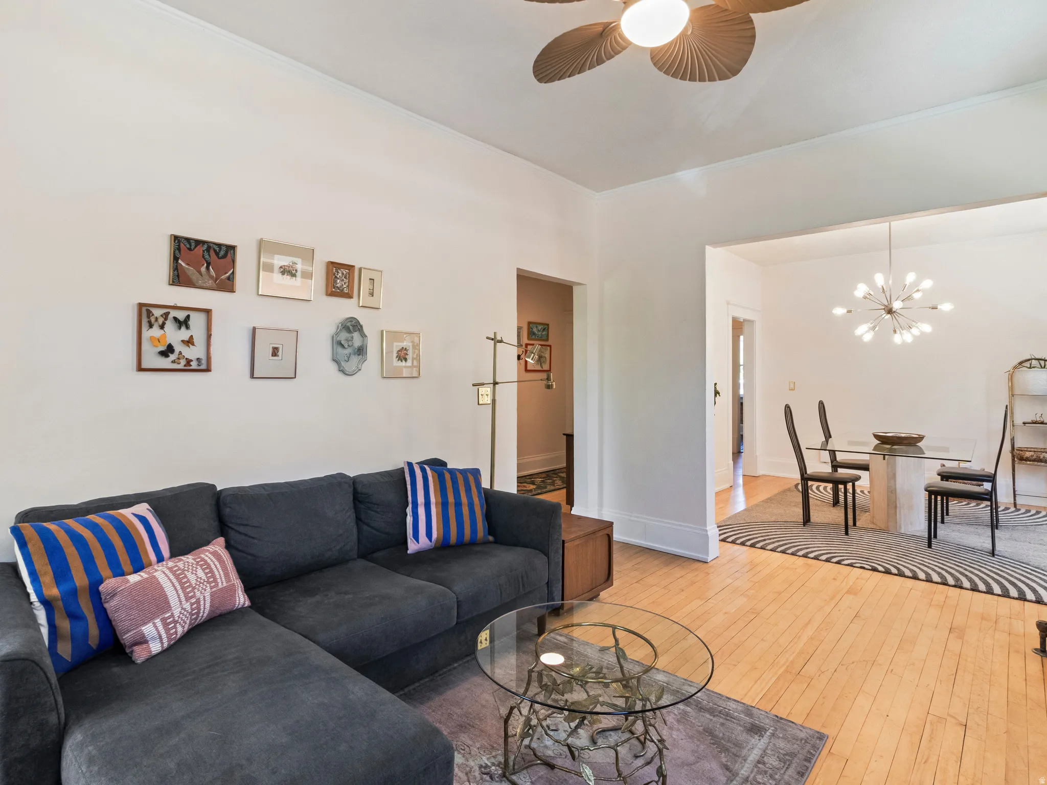 Hardwood flooring extends throughout this living area, featuring a ceiling fan with integrated lighting
