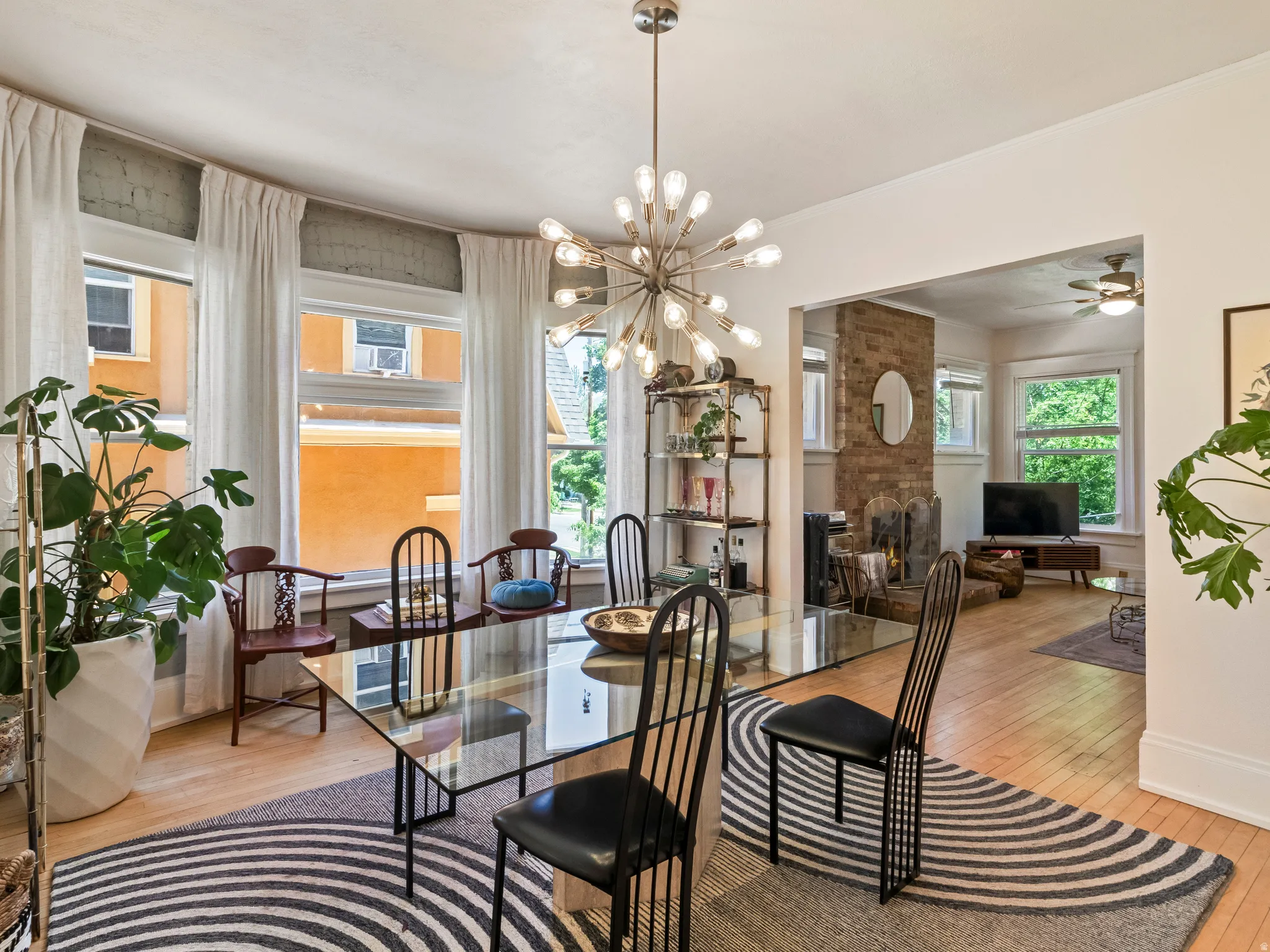 Dining space featuring hardwood flooring, a contemporary chandelier, and a curved wall of multiple windows