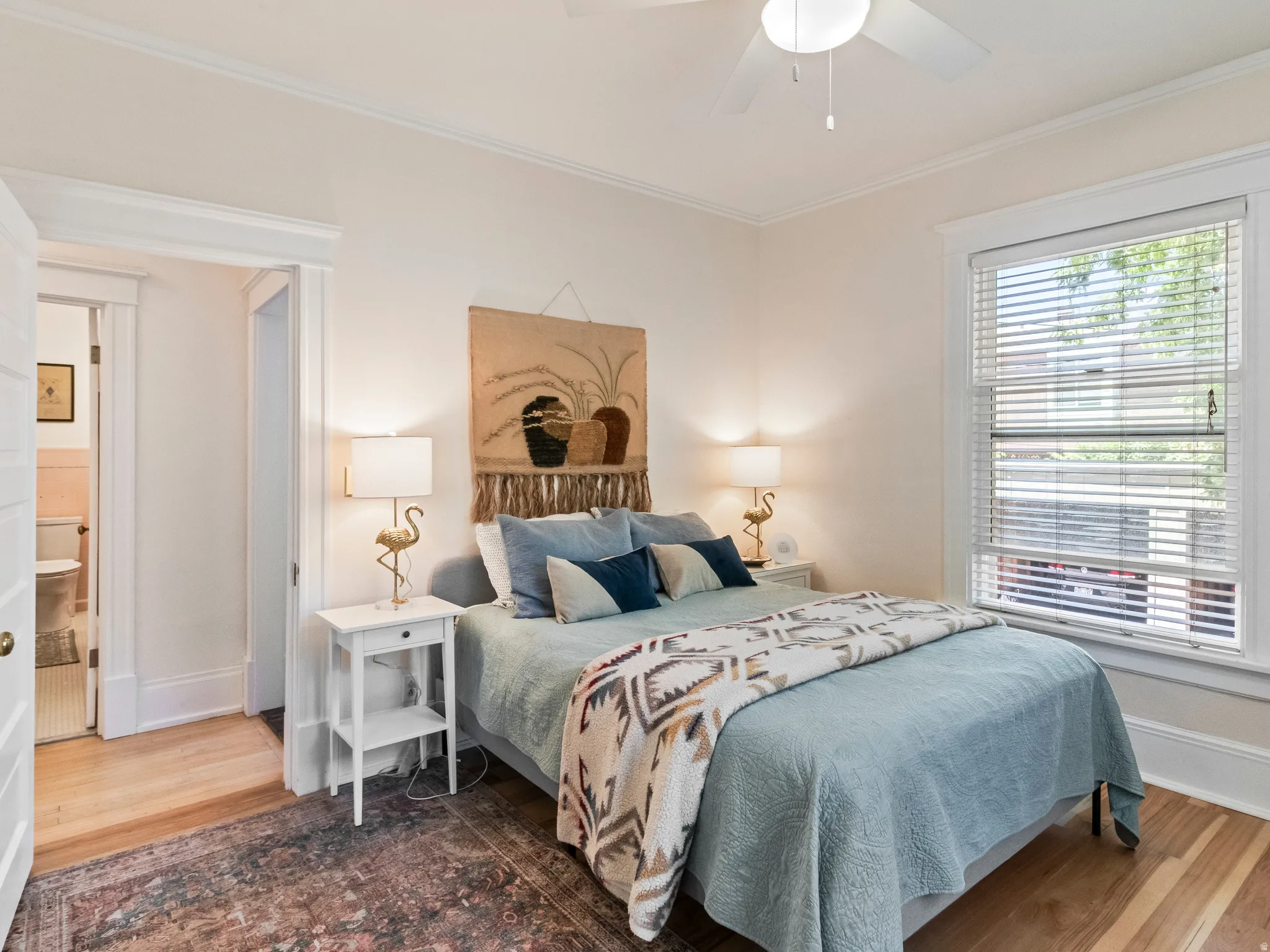Bedroom featuring a ceiling fan, wood-finish flooring, a window with blinds, and white trim