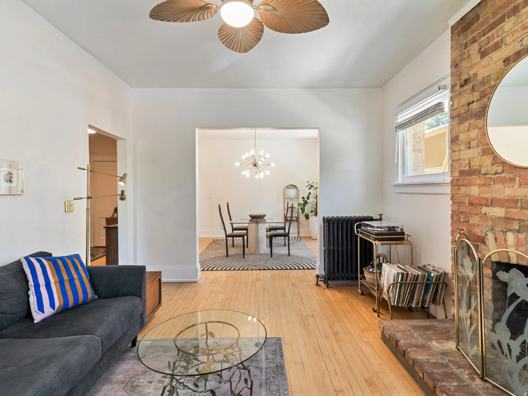 Hardwood flooring extends throughout this space, featuring a brick fireplace with a decorative screen