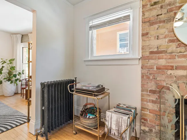 Exposed brick wall feature with a white window frame and a cast iron radiator
