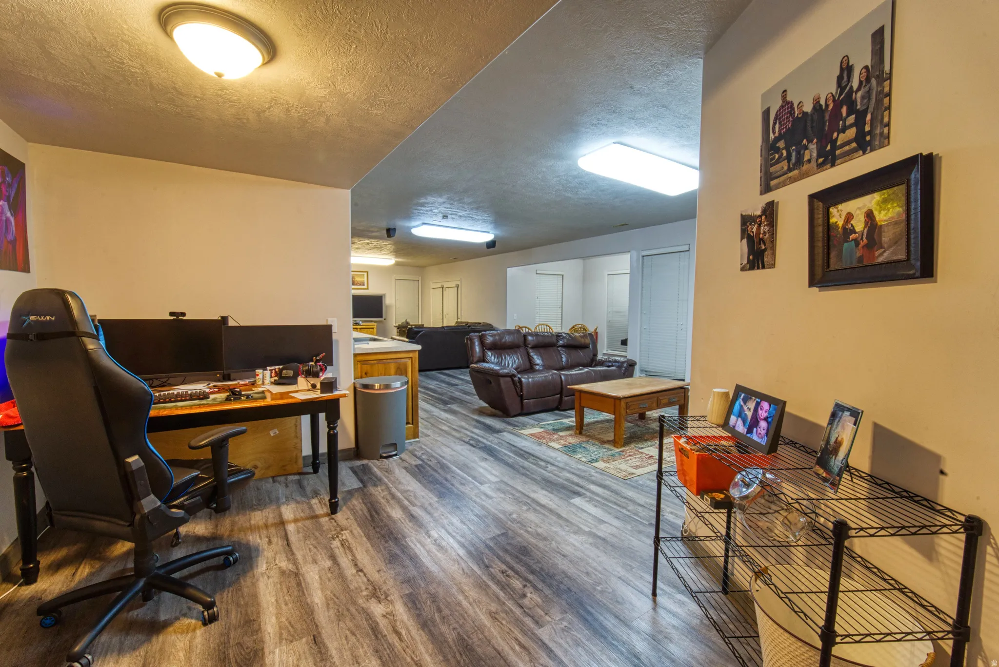 Expansive open-concept room featuring wood-finish flooring, recessed lighting, and a built-in partial wall