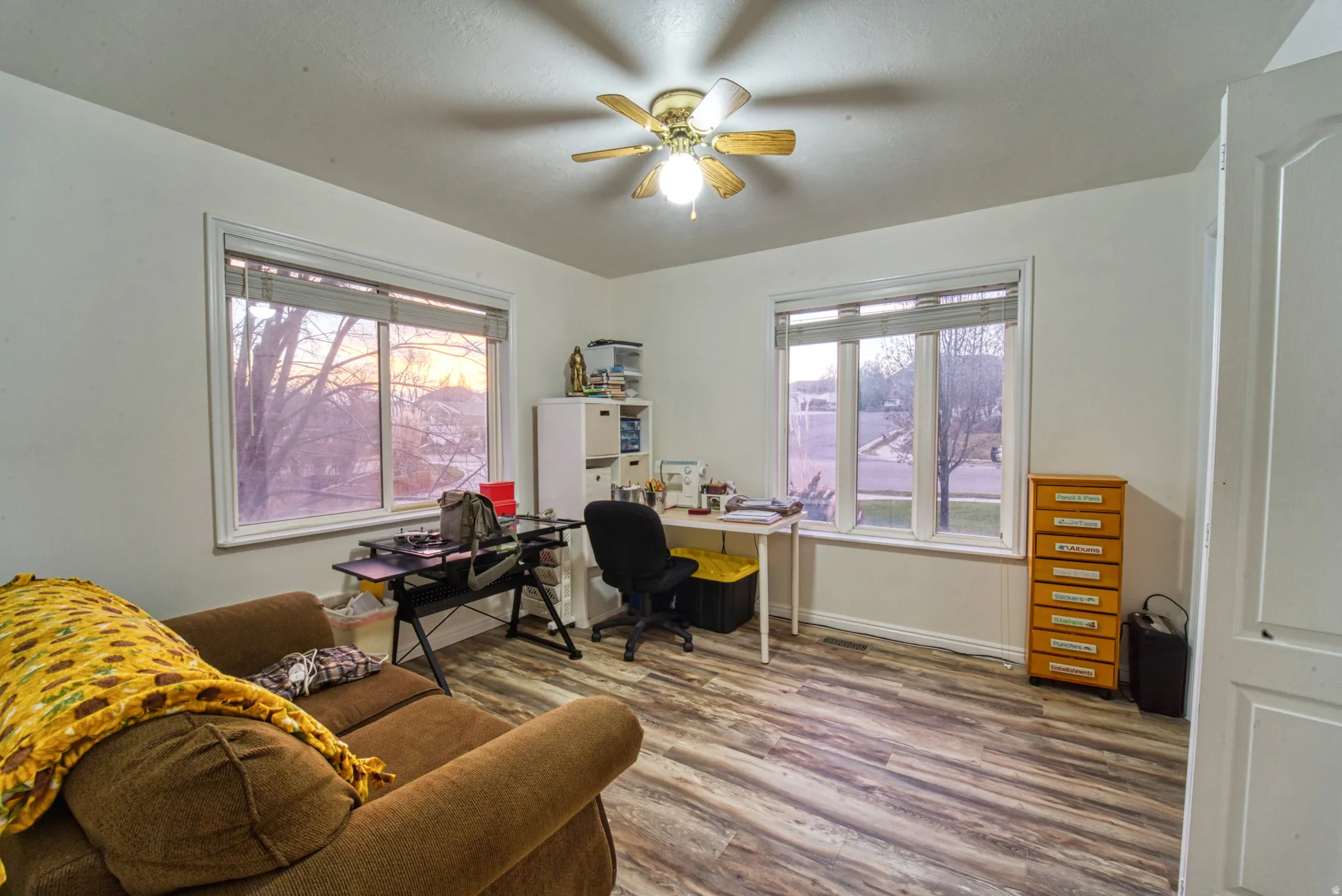 Room featuring wood-finish flooring, white walls, and a ceiling fan with integrated lighting